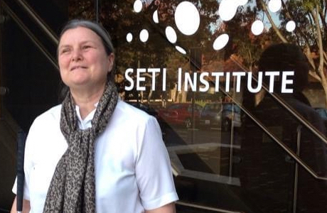 Photo of Sheri standing in front of the  SETI Institute, smiling, holding her white cane.